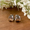 A pair of gold Grace hoops, featuring a chunky, domed design, displayed on a textured wooden surface with white floral accents. The earrings are statement huggie hoops, available in Ottawa, Ontario, Canada.