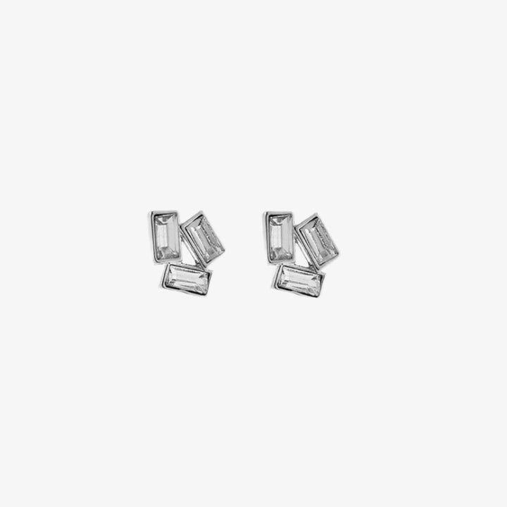 A pair of silver stud earrings with multiple rectangular crystals on a pink card with the brand name 