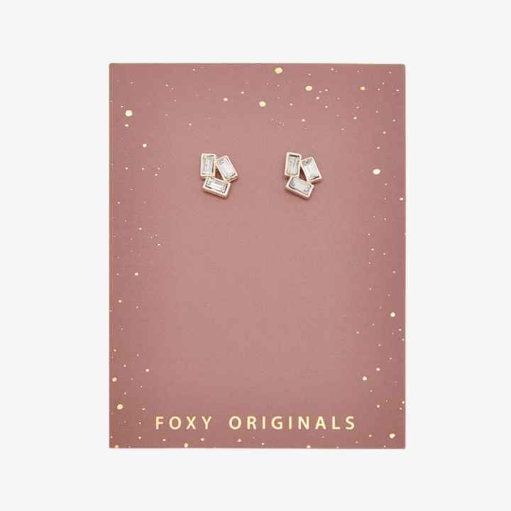 A pair of silver stud earrings with multiple rectangular crystals on a pink card with the brand name 