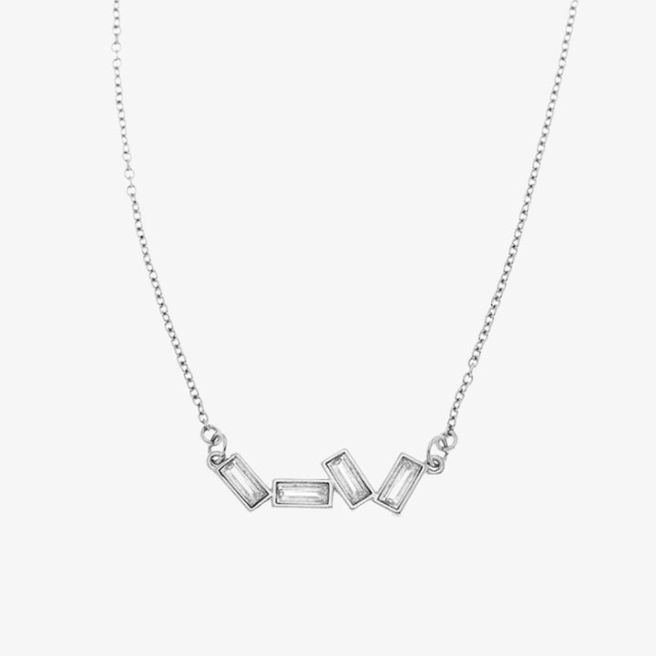 A silver necklace with several rectangular-shaped crystals on a pink card with the brand name 