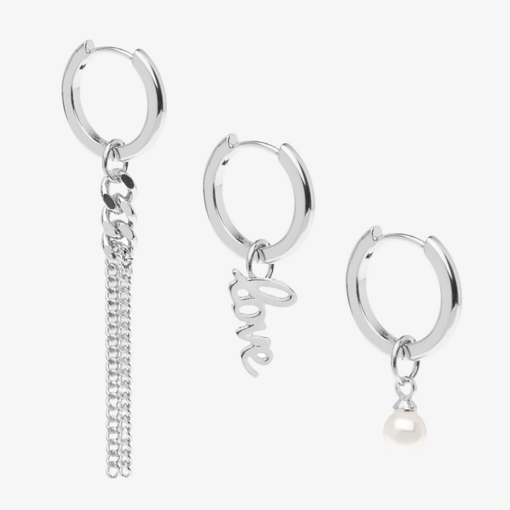 A set of silver earrings with interchangeable charms. The set includes two pairs of silver hoop earrings and three charms: a pearl, the word 