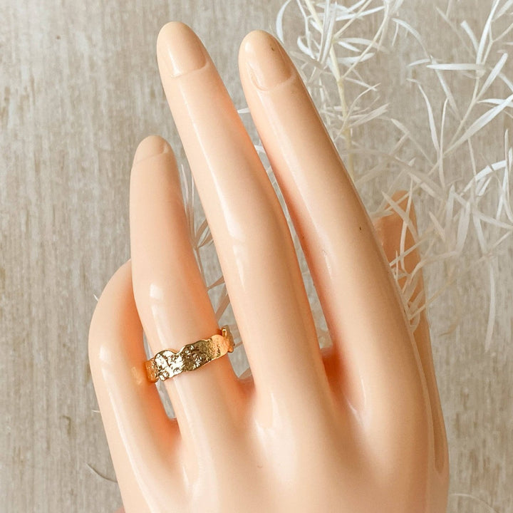 A silver Malta ring, featuring a textured, organic design, displayed on a white, hand-shaped jewelry holder. The ring is an open, adjustable style, available in Ottawa, Ontario, Canada.