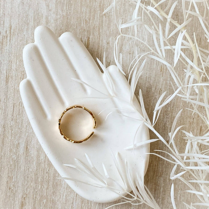 A silver Malta ring, featuring a textured, organic design, displayed on a white, hand-shaped jewelry holder. The ring is an open, adjustable style, available in Ottawa, Ontario, Canada.