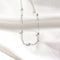 A silver chain necklace with multiple small, round beads evenly spaced along the chain. The necklace is resting on a white surface.