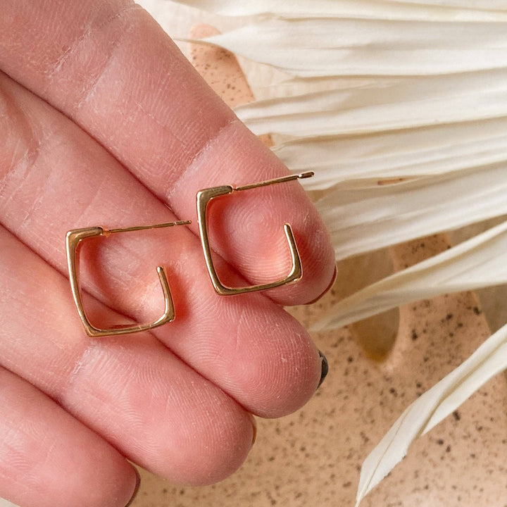 A pair of silver squared hoop earrings, featuring a chunky, geometric square design, displayed on a white, textured surface. The earrings are modern and minimalist, available in Ottawa, Ontario, Canada.