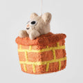 A felt ornament of a cat peeking out of a chimney.