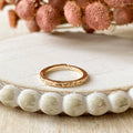 A gold-plated ring with a textured, hammered surface. The ring is gold plated and adjustable.