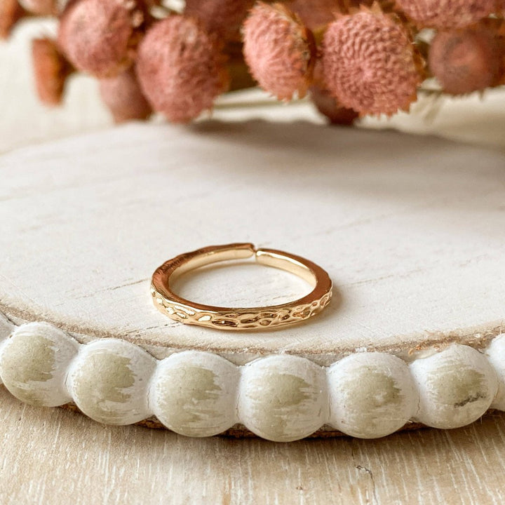 A gold-plated ring with a textured, hammered surface. The ring is gold plated and adjustable.