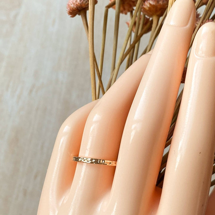 A gold-plated ring with a textured, hammered surface. The ring is gold plated and adjustable.
