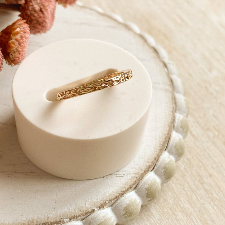 A gold-plated ring with a textured, hammered surface. The ring is gold plated and adjustable.