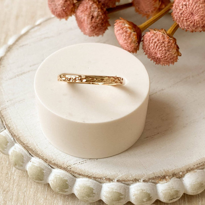 A gold-plated ring with a textured, hammered surface. The ring is gold plated and adjustable.
