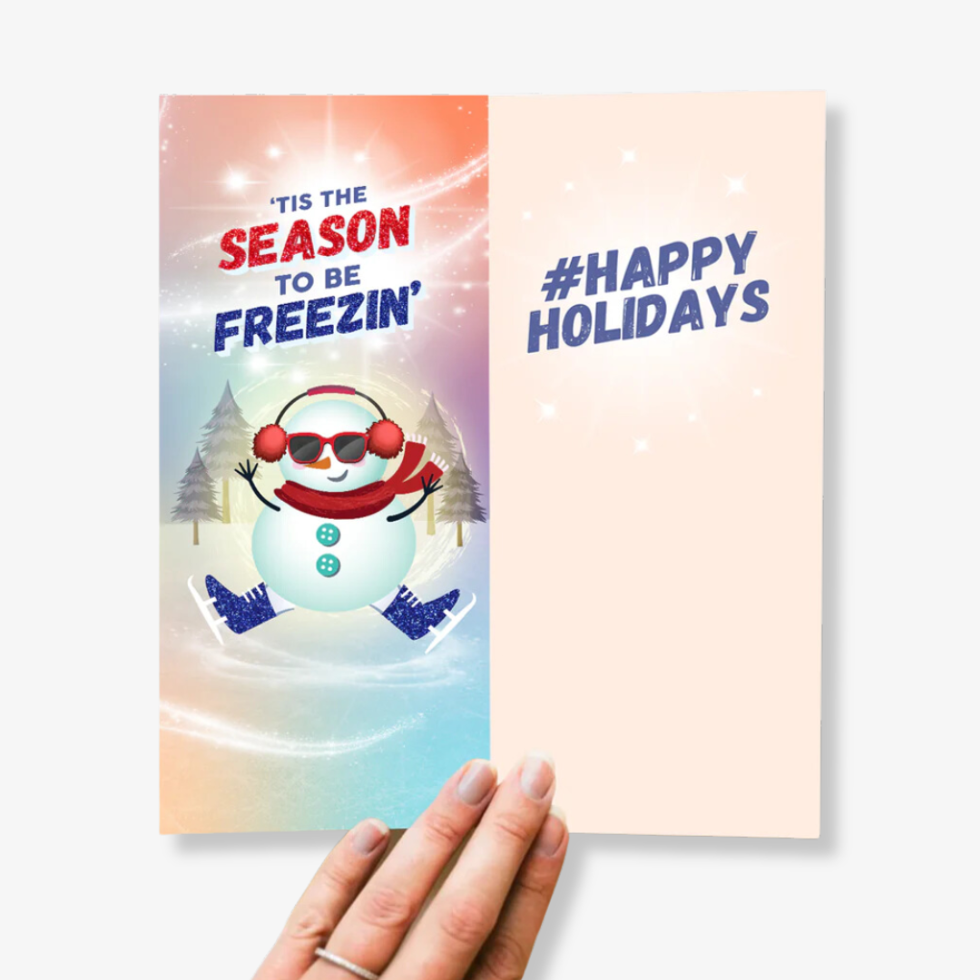 A pair of colorful socks with a winter theme, packaged with a card. The socks feature a snowman ice skating and taking a selfie, with the hashtag "#SNOW FILTER" printed on the card.