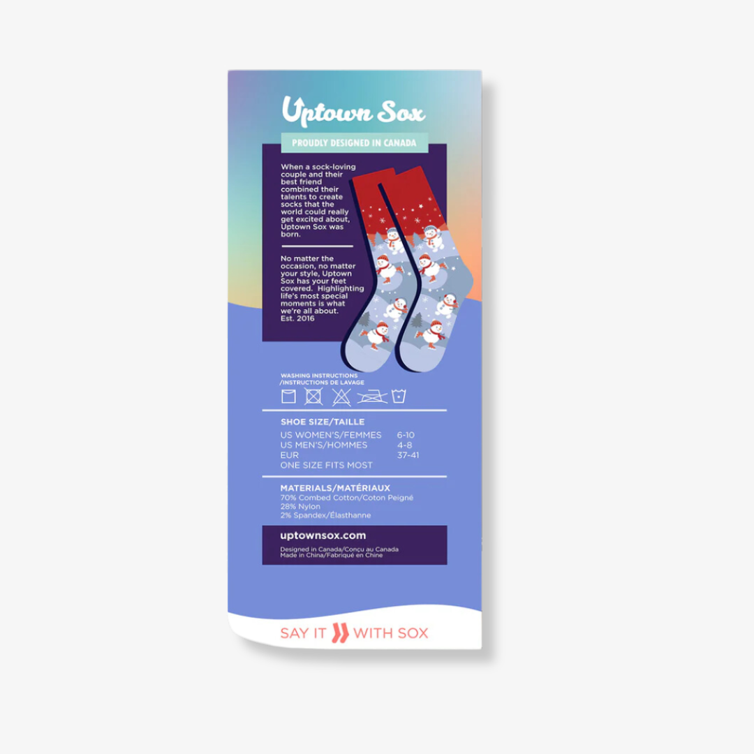 A pair of colorful socks with a winter theme, packaged with a card. The socks feature a snowman ice skating and taking a selfie, with the hashtag "#SNOW FILTER" printed on the card.