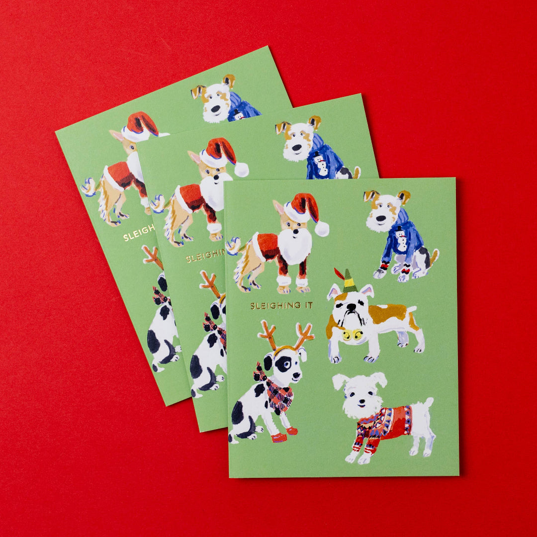 Three green greeting cards with Christmas-themed dog illustrations on a red background