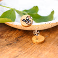 A pair of wooden earrings featuring a snake design in brown, black, and white.