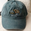 Blue cap with turtle design and 'Slowly but Surely' text on a white surface.