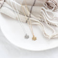 Two snowflake-shaped necklaces on a white plate with a neutral background