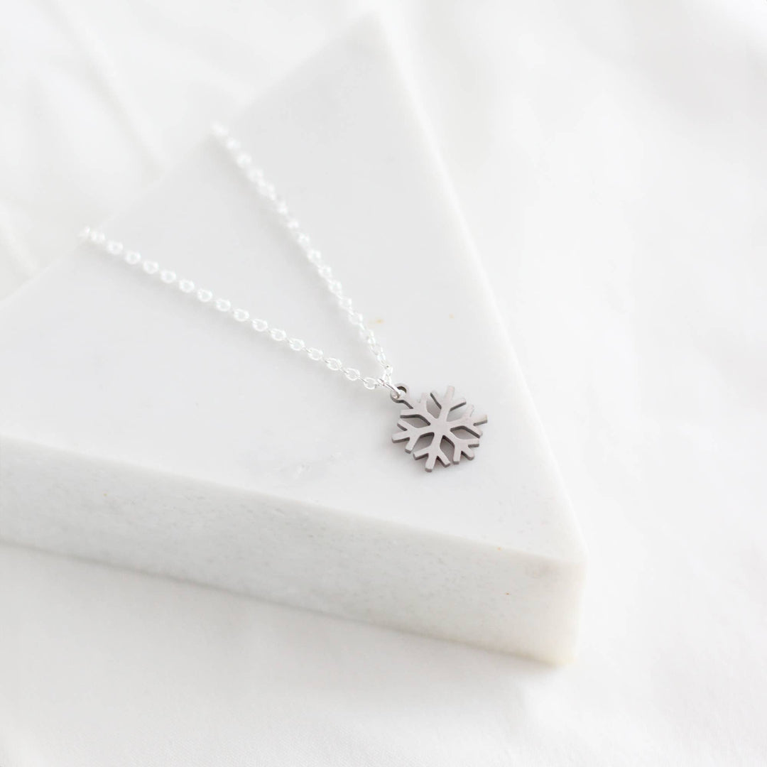 Silver snowflake necklace on a white fabric background
