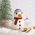 Small snowman figurine with a tree and snow on a light background