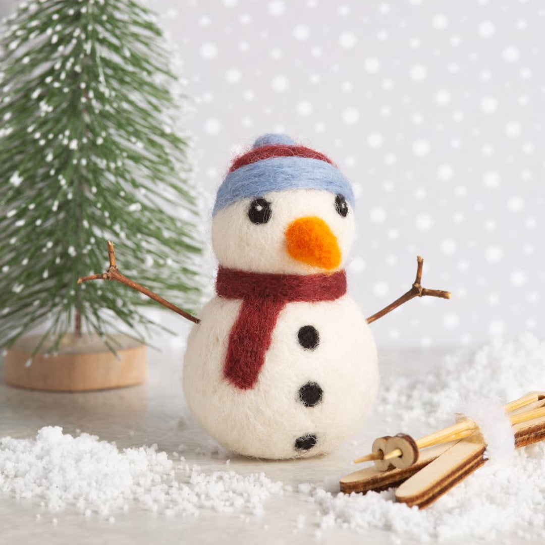 Small snowman figurine with a tree and snow on a light background