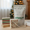 Soap So Co. bubble bag with two soap bars on a wooden surface, Christmas tree in the background