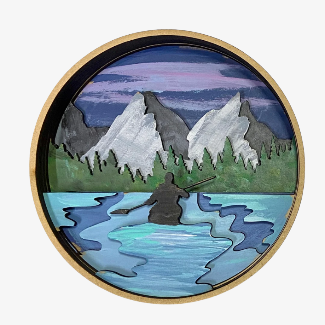 Round decorative piece with a mountain and lake scene, featuring a person in a kayak.