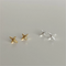 A set of silver and gold sparkle stud earrings, each featuring a minimalist four-pointed star or starfish-like design, displayed on a light grey surface. These celestial earrings are available in Ottawa, Ontario, Canada.