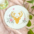Decorative plate with gold deer head design on a textured surface with leaves.