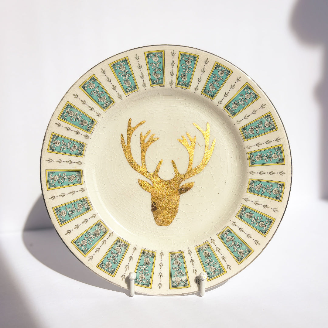 Decorative plate with gold deer head design and floral patterns on a white background