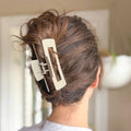 Person with a hair clip in their hair against a blurred background