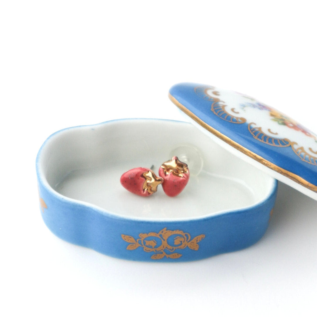 Blue jewelry box with strawberry-shaped earrings on a white background