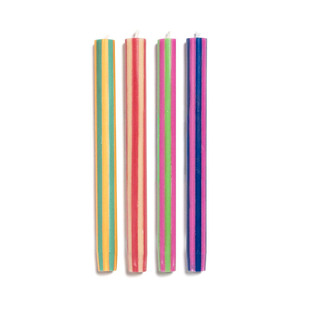 Four slim striped candles standing vertically on a plain white background. From left to right, the candle colors are yellow and green, orange and pink, light green and pink, and blue and purple.