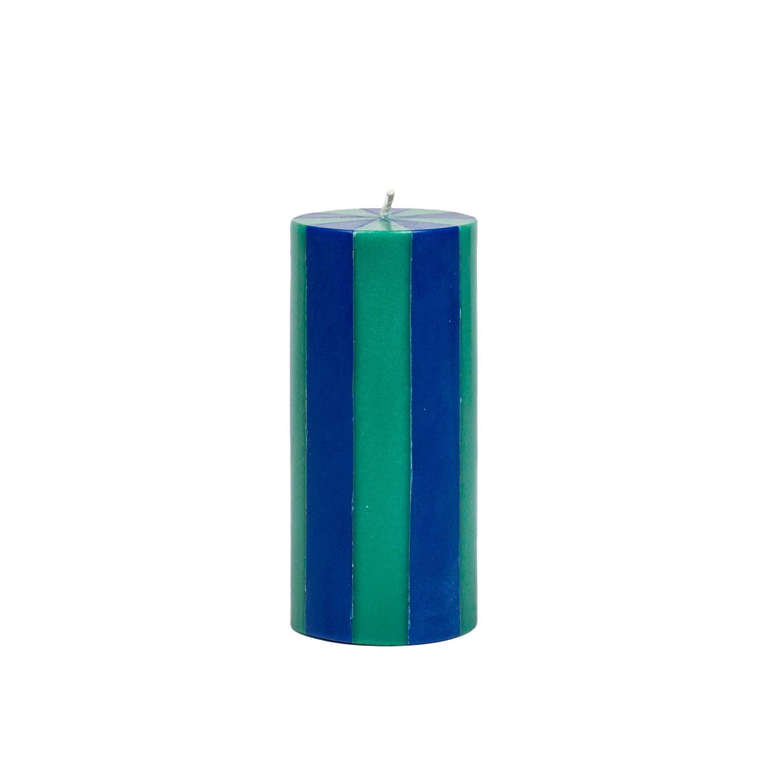 Cylindrical candle with blue and green stripes on a white background