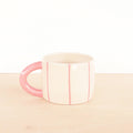Mug with pink handle and interior on a beige surface