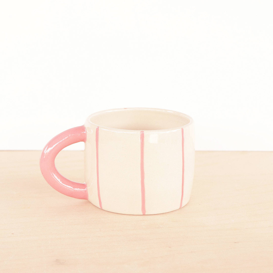Mug with pink handle and interior on a beige surface