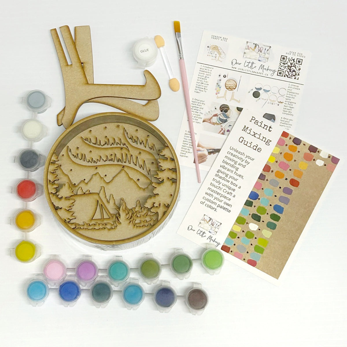 Wooden ornament with engraved design, paint tubes, brushes, and instructions on a white background