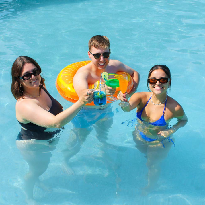 A Summer Cocktail Bomb Variety Pack, featuring colorful, fruit-flavored drink mixers in a white box, with a hand picking up a yellow cocktail bomb. The image includes strawberries, pineapples, and limes against a bright blue background. Available in Ottawa, Ontario, Canada.