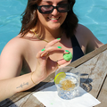 A Summer Cocktail Bomb Variety Pack, featuring colorful, fruit-flavored drink mixers in a white box, with a hand picking up a yellow cocktail bomb. The image includes strawberries, pineapples, and limes against a bright blue background. Available in Ottawa, Ontario, Canada.