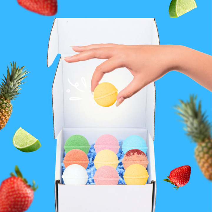 A Summer Cocktail Bomb Variety Pack, featuring colorful, fruit-flavored drink mixers in a white box, with a hand picking up a yellow cocktail bomb. The image includes strawberries, pineapples, and limes against a bright blue background. Available in Ottawa, Ontario, Canada.