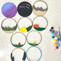 Set of embroidered hoop art with various designs on a textured surface, accompanied by a paint palette.