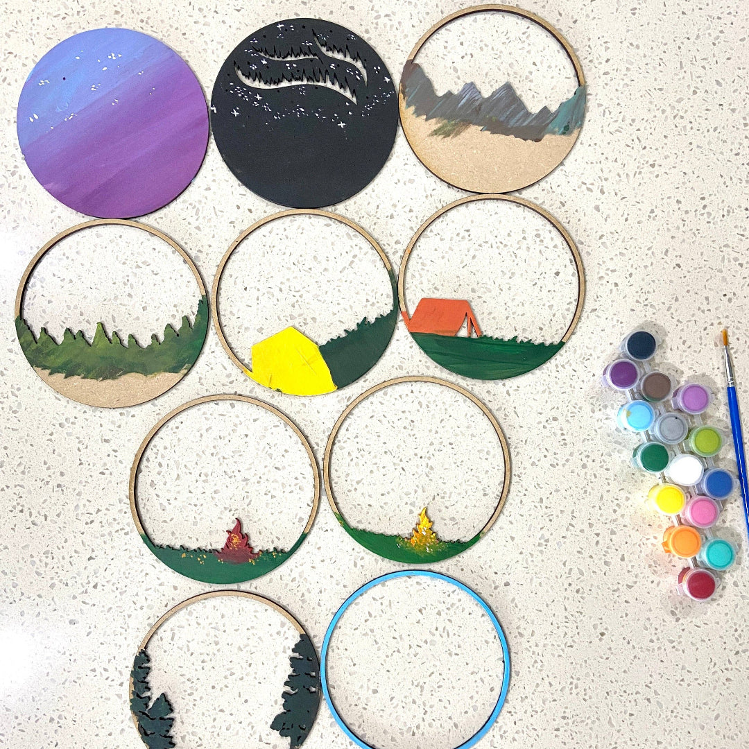 Set of embroidered hoop art with various designs on a textured surface, accompanied by a paint palette.