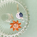 Sun and moon earrings on a decorative glass plate with a light green background