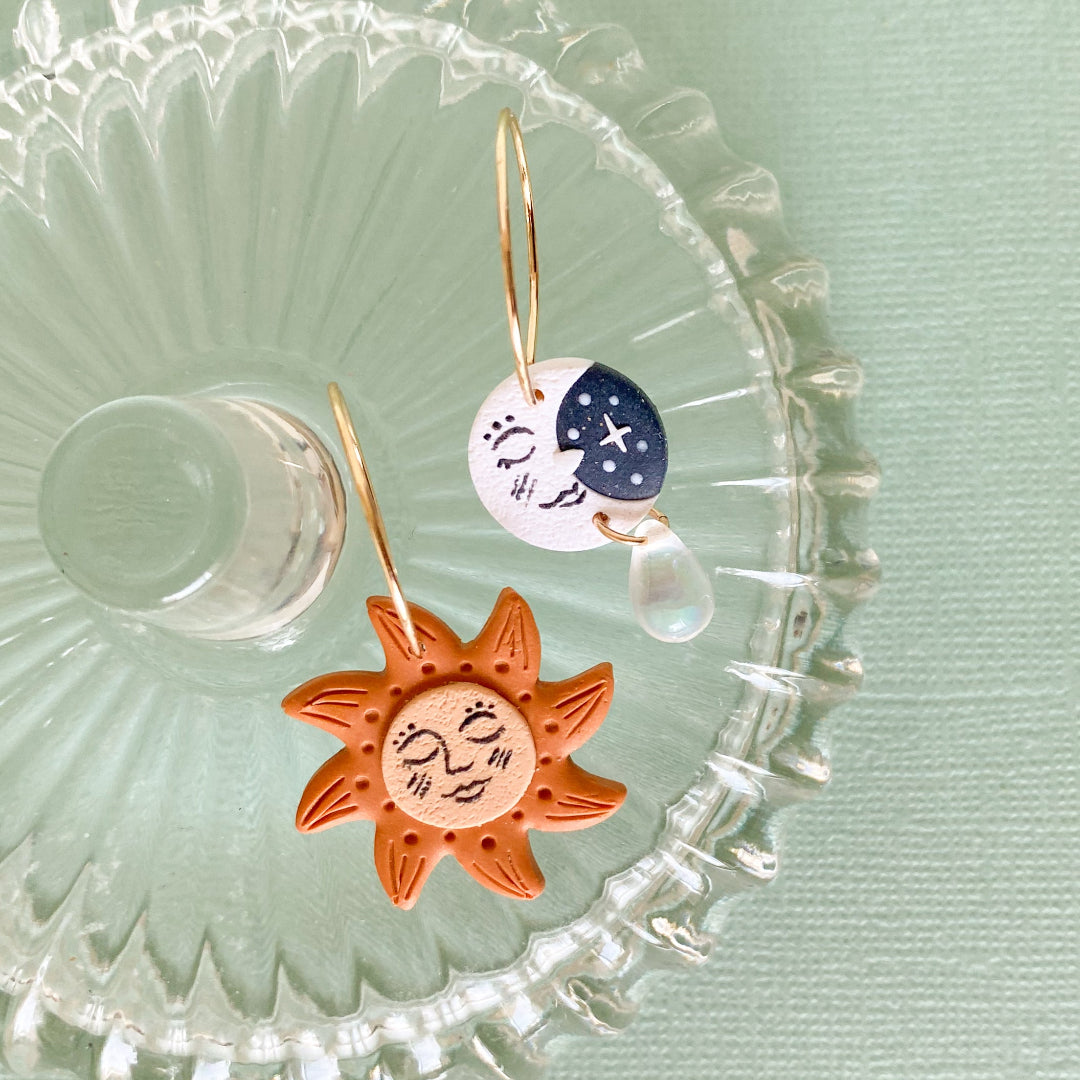 Sun and moon earrings on a decorative glass plate with a light green background