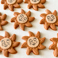 Sun-shaped cookies with face designs on a white surface