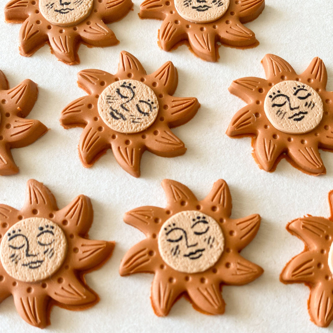 Sun-shaped cookies with face designs on a white surface