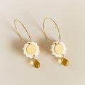 Pair of earrings with gold and white design on a beige background