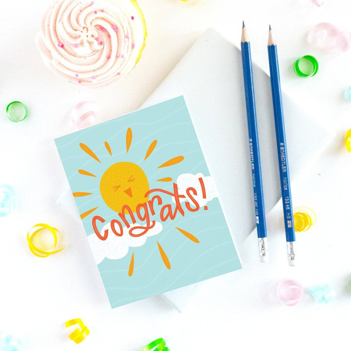 A congratulations card featuring a smiling sun with rays shining on clouds. The text 