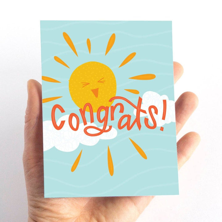 A congratulations card featuring a smiling sun with rays shining on clouds. The text 