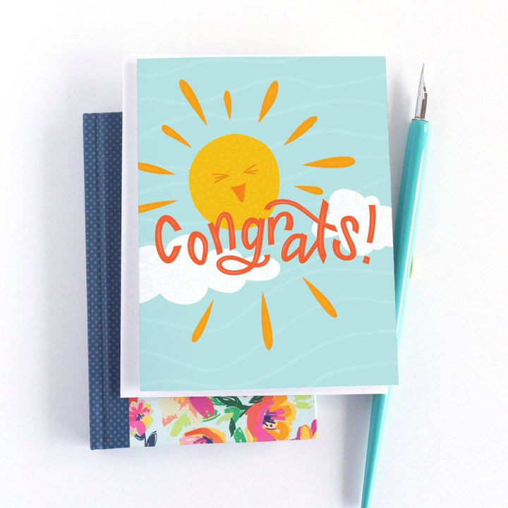 A congratulations card featuring a smiling sun with rays shining on clouds. The text 