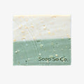 Two-tone soap bar with visible texture on a black background, branded 'Soap So Co'.